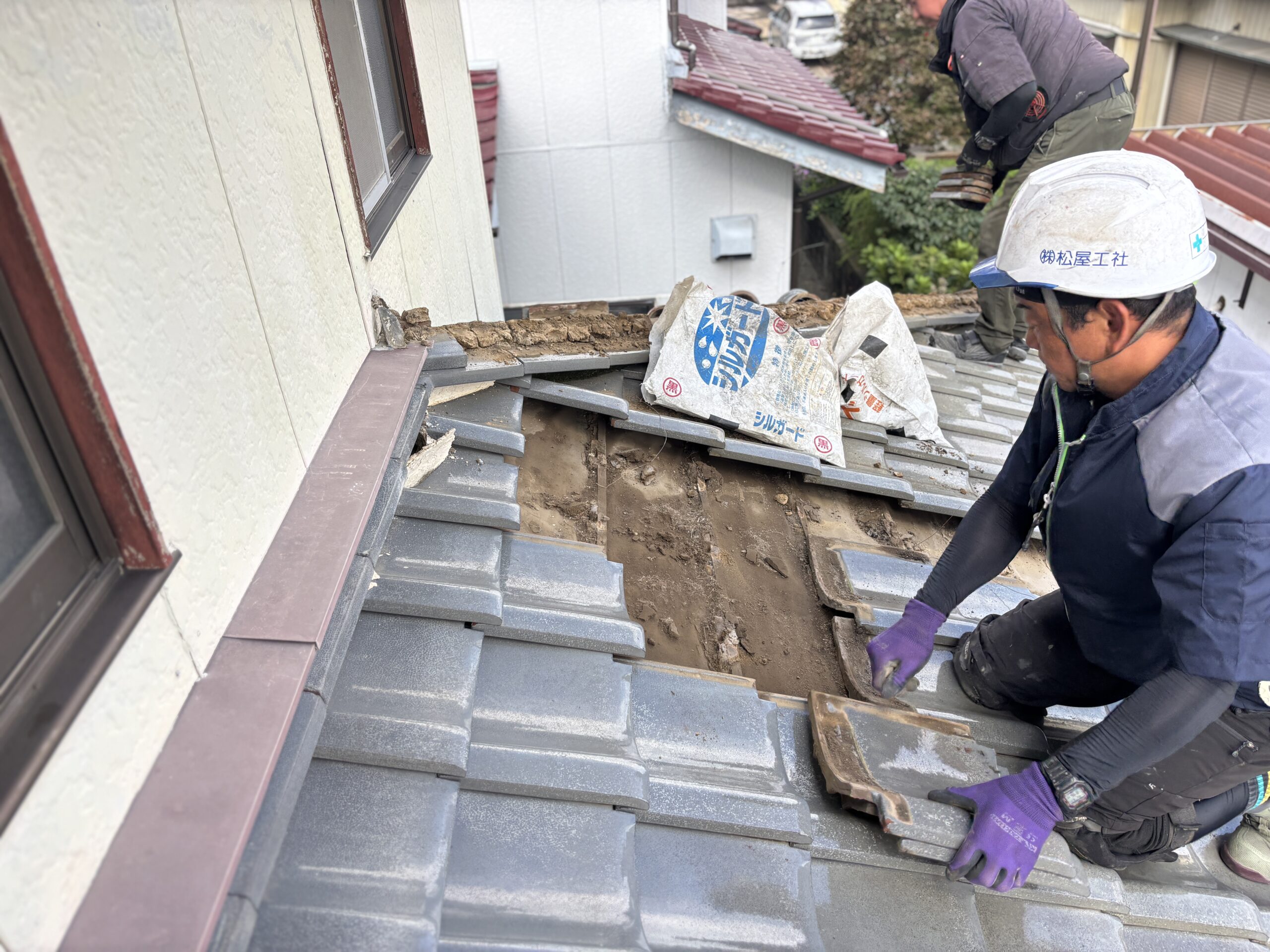 雨漏り箇所の周囲を確認しながら瓦を一枚ずつ取り外す作業